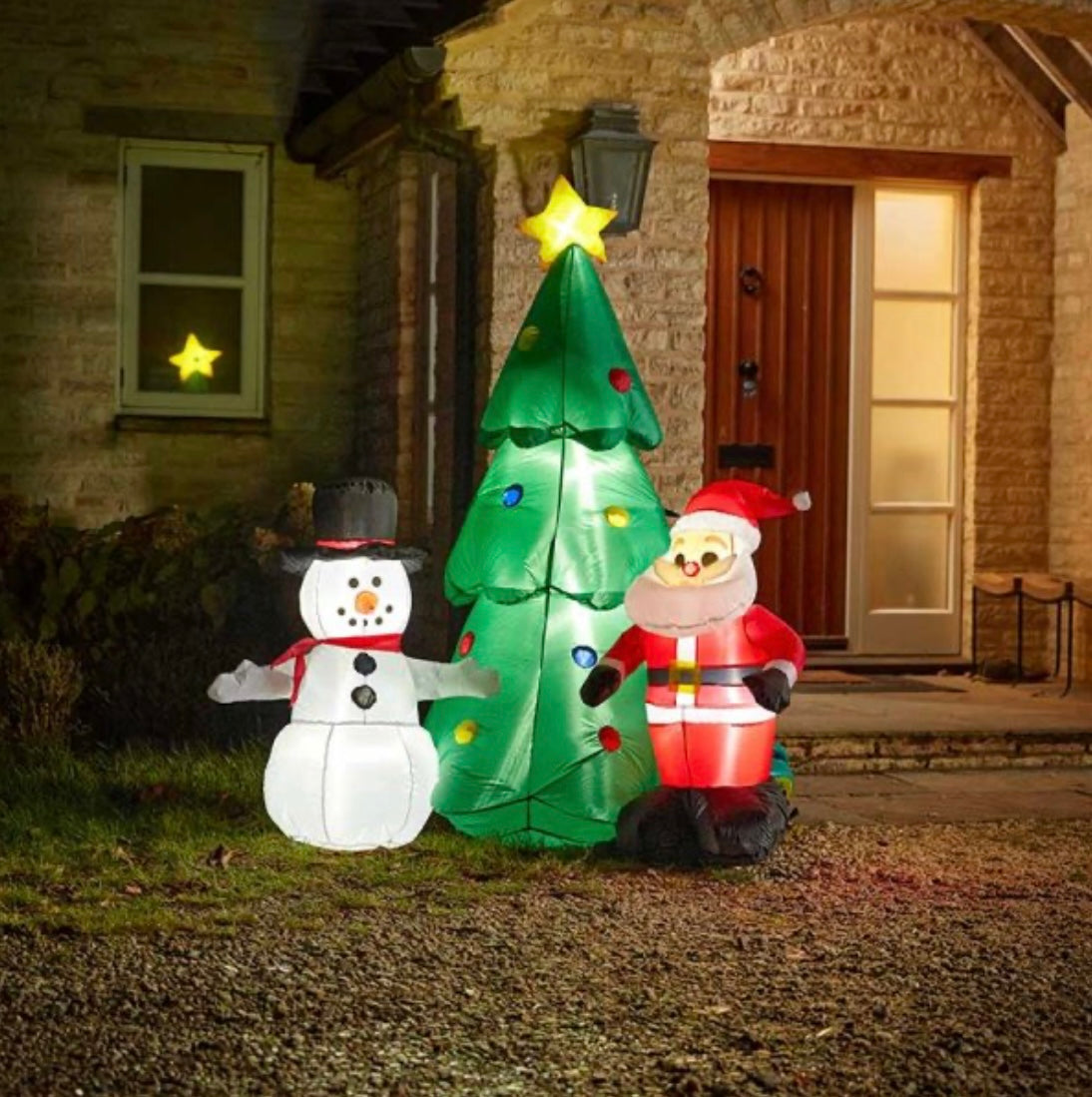 A self-inflating Christmas tree featuring a Santa Claus and a snowman, with LED lights, displayed on a front lawn.