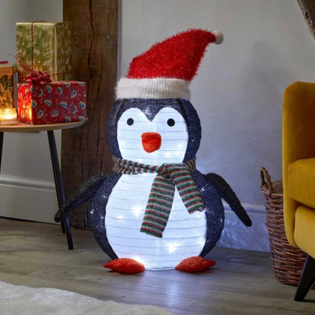 A decorative penguin-shaped Christmas ornament with a Santa hat and a scarf, featuring multicolored lights.