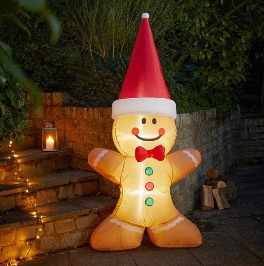 A self-inflating gingerbread man with a Santa hat standing on a step, illuminated by cool white LEDs.