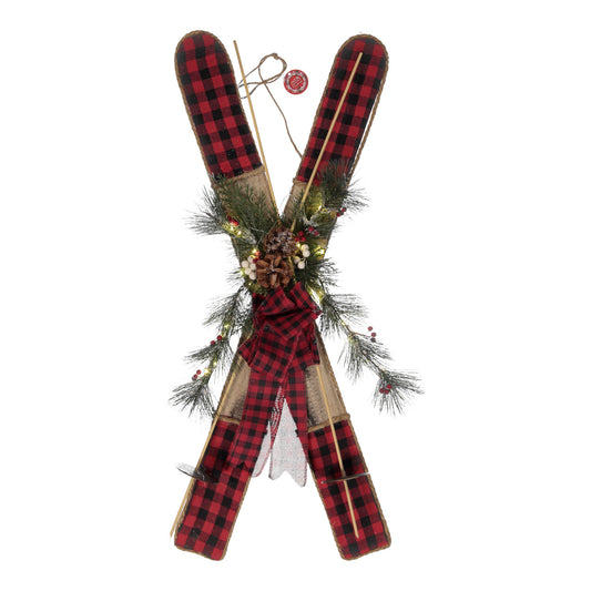 Decorative skis with plaid pattern and greenery on a white background