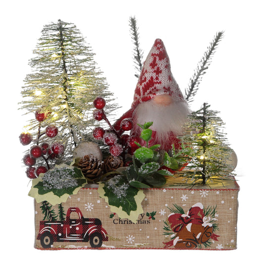 Decorative Christmas scene with a gnome, trees, and berries on a box.