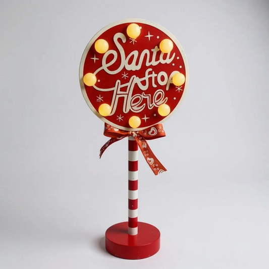 Decorative sign with 'Santa Stop Here' text on a red background